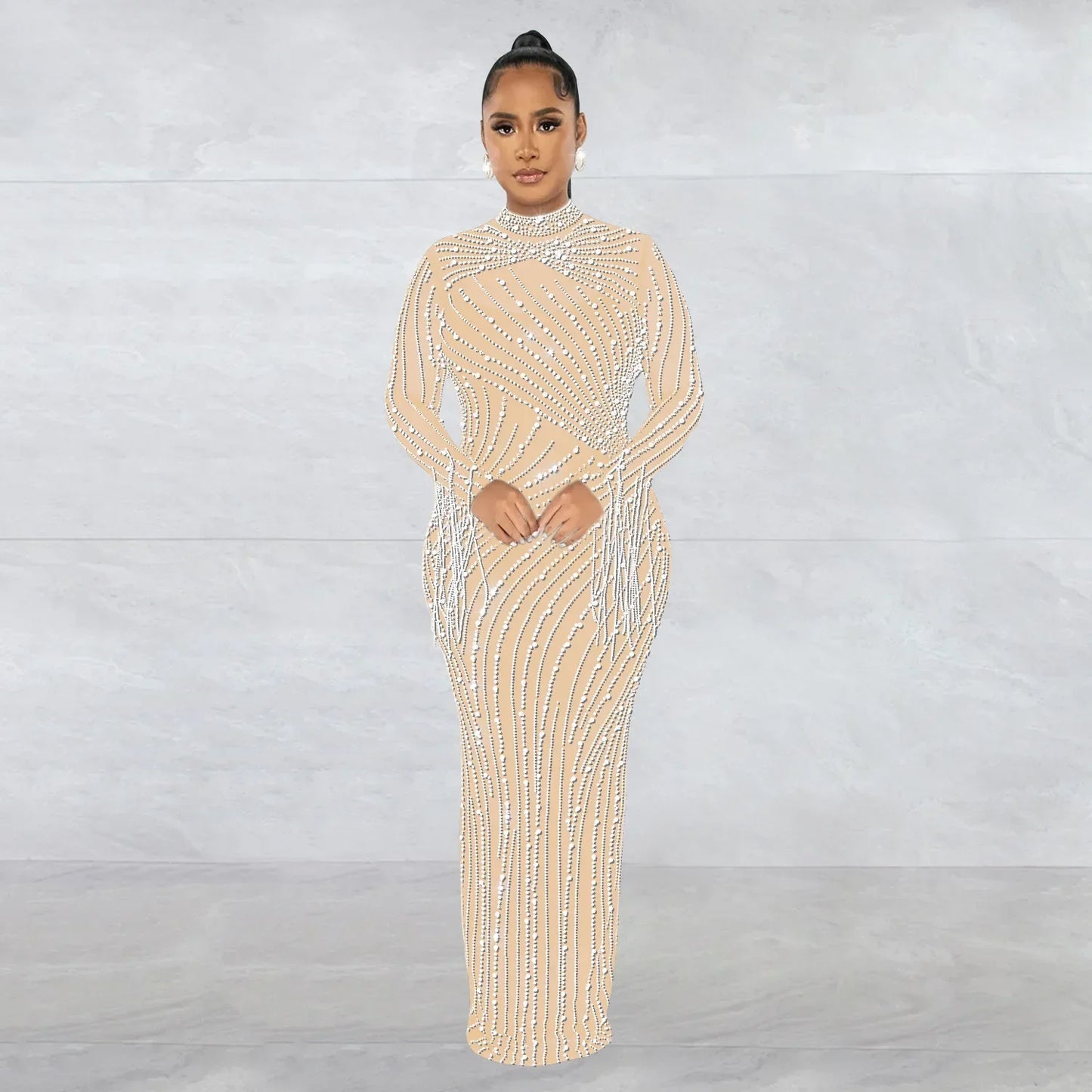 Woman in a nude crystal embellished gown standing against a light grey background