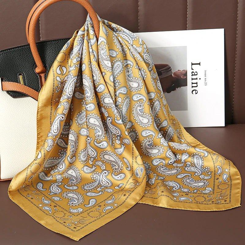 Yellow paisley silk scarf draped on a handbag, with a magazine on a brown leather seat.