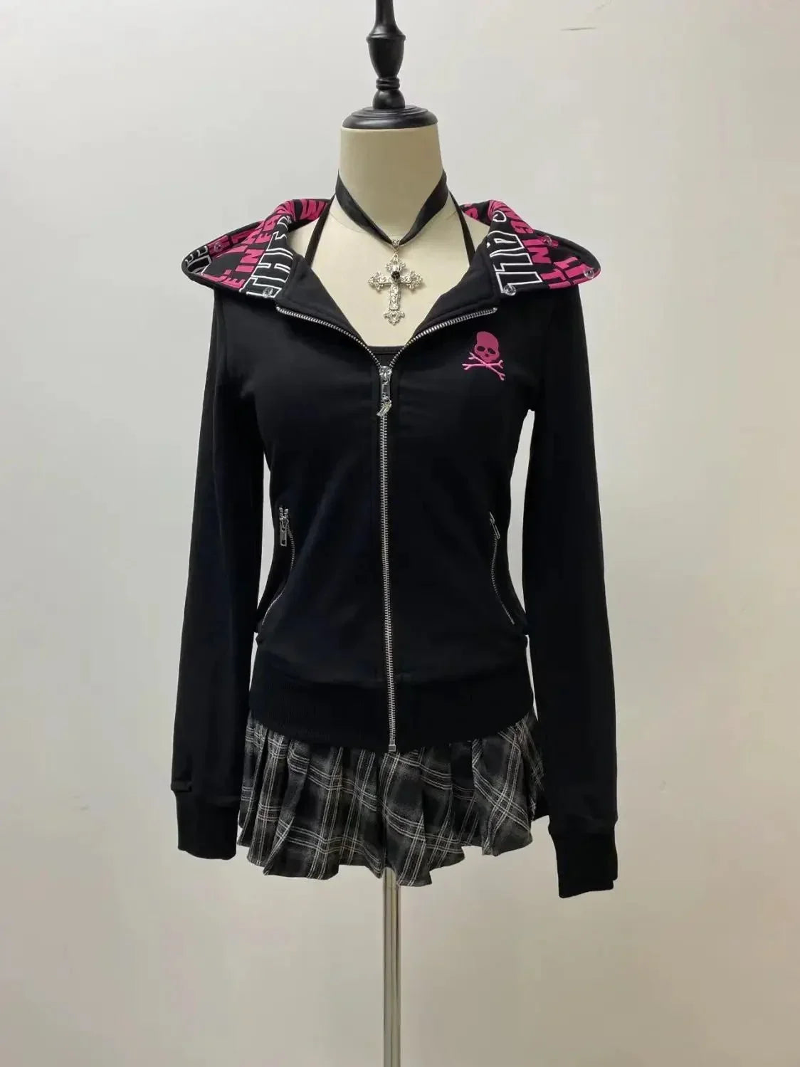 Black hoodie with pink skull graphic and plaid skirt on mannequin, gothic fashion style
