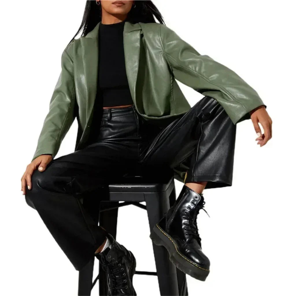 Woman wearing green faux leather blazer, black turtleneck, black pants, and boots
