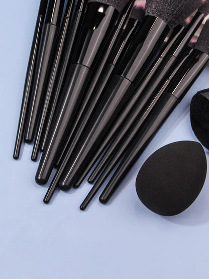 Black luxury makeup brush set with blending sponge on light blue background