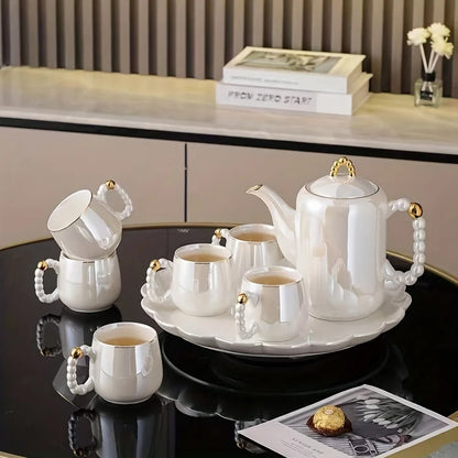 Pearl glazed porcelain tea set with gold accents on black table in modern home decor setting