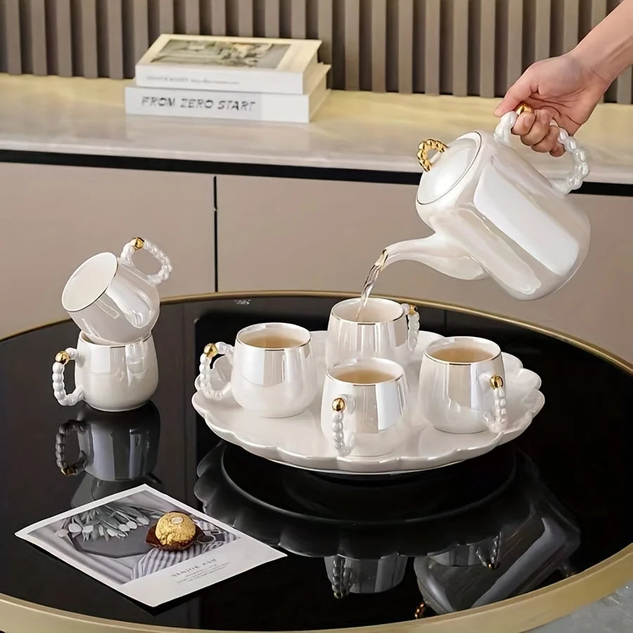 Elegant pearl glazed European style porcelain tea set with gold-accented handles on black glass table