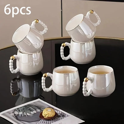 6-piece pearl glazed European-style porcelain tea cup set with gold accent handles on black table