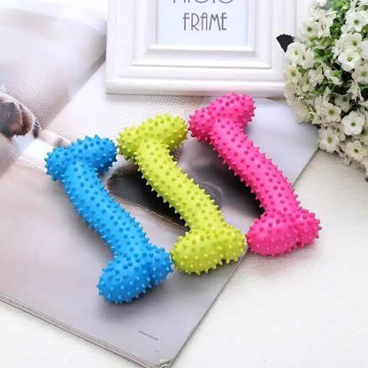 Three colorful rubber chew toys for small dogs shaped like bones with spikes in blue, yellow, and pink on a magazine and white surface