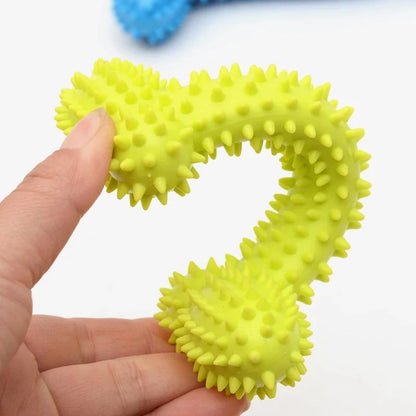 Hand holding yellow rubber spiked dog chew toy shaped like a question mark on white background