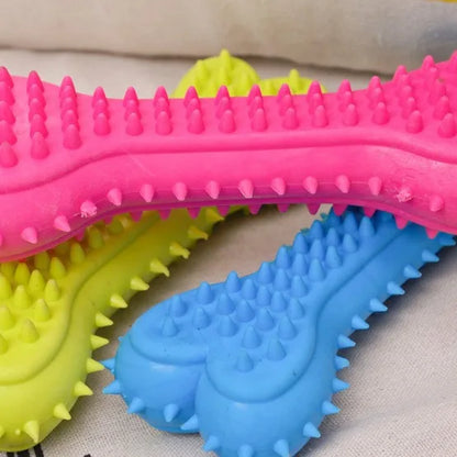 Colorful rubber spiked chew toys for small dogs in pink, yellow, and blue on a fabric surface