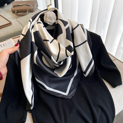 Black and white geometric silk scarf draped on a black sweater, chic fashion accessory