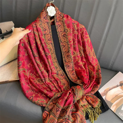 Red paisley pashmina shawl with fringe, draped on a grey sofa, perfect for women