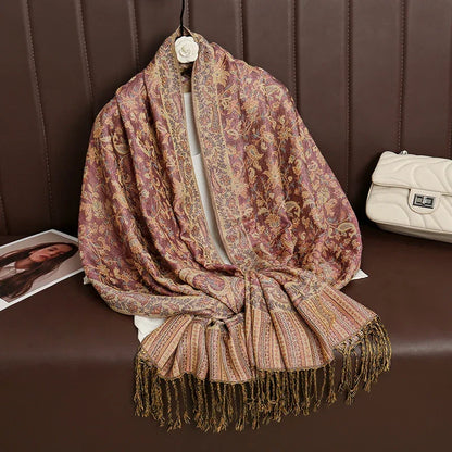 Paisley floral shawl with gold fringe on brown cushioned bench, cream purse beside