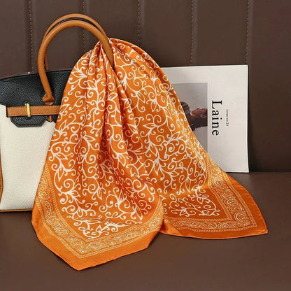 Orange paisley silk scarf draped on handbag, modern accessories, elegant fashion style
