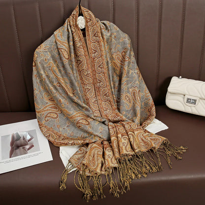 Paisley patterned scarf with gold fringe on brown seat, next to a white quilted handbag