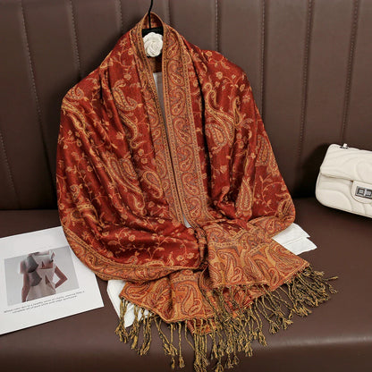 Red paisley shawl with gold fringe on brown couch, white quilted handbag beside it