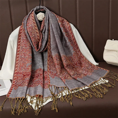 Paisley patterned pashmina shawl with red and gray tones and tassel fringe on display
