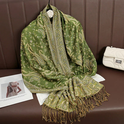 Green paisley shawl with fringe on brown sofa, white purse and magazine nearby