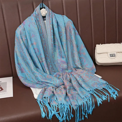 Blue paisley patterned scarf with fringe on brown bench, white purse beside