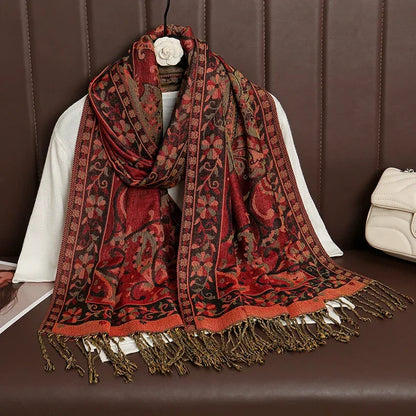 Red and black paisley floral pashmina scarf with fringe detail on brown couch