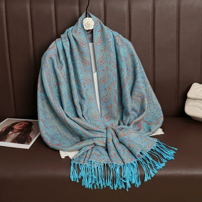 Light blue paisley shawl with fringes draped on brown sofa, fashion accessory display