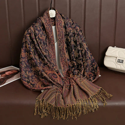 Paisley patterned shawl with gold fringe on brown couch, cream purse beside it