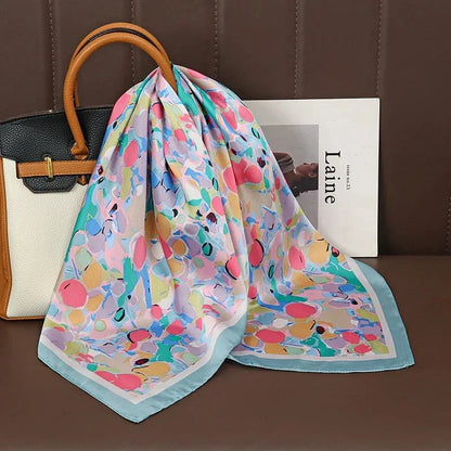 Colorful abstract silk scarf draped on a handbag with magazine on brown leather seat