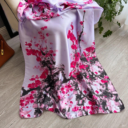 Silk scarf with pink cherry blossom print draped on a chair, on wooden floor