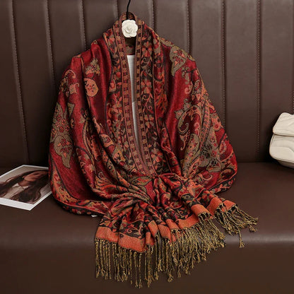 Red and gold paisley patterned shawl with fringe on brown leather sofa