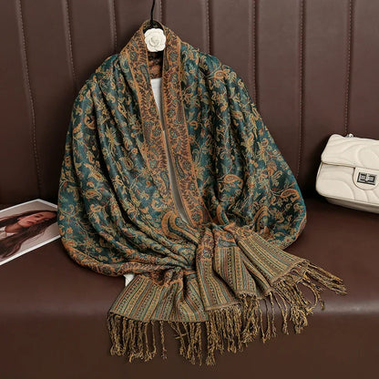 Green and gold paisley shawl with fringe on brown sofa, next to white quilted purse