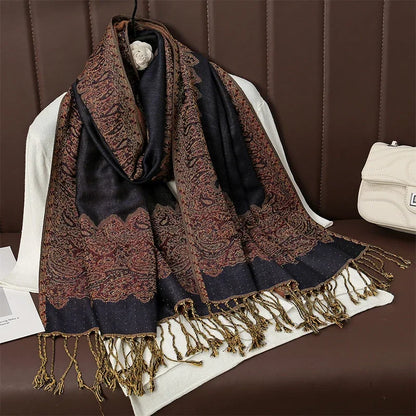 Black and red paisley scarf with gold fringe on brown leather bench and white purse