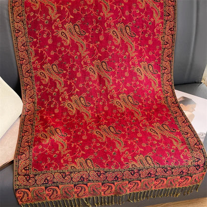 Red paisley patterned pashmina shawl with ornate fringe on a gray sofa