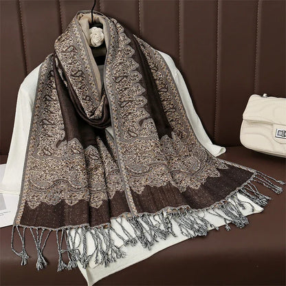 Elegant brown paisley pashmina scarf with fringes displayed on a brown leather sofa.