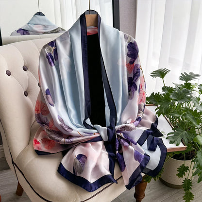 Floral silk scarf with navy border draped on cream chair by window with green plant