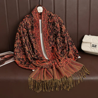 Red and black paisley shawl with fringe on brown leather bench