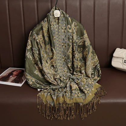 Green and gold paisley patterned scarf with fringe, displayed on a brown bench