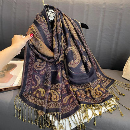 Black paisley scarf with gold and maroon embroidery and tasseled fringes on a sofa