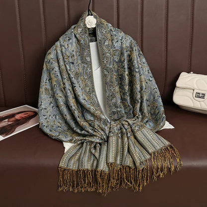 Paisley patterned fringed scarf draped on a brown bench with a white handbag beside it