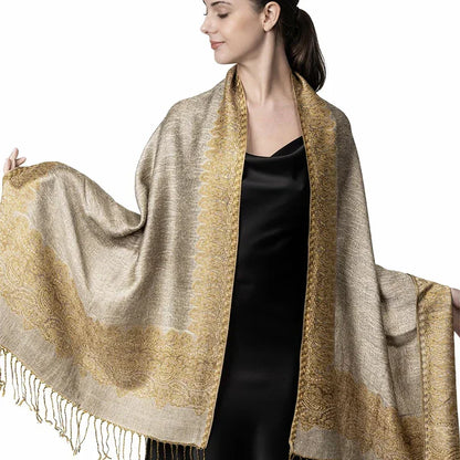 Woman wearing gold and beige paisley pashmina shawl over black dress against white background