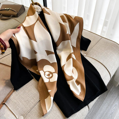 Brown and white floral silk scarf draped over black clothing on beige sofa