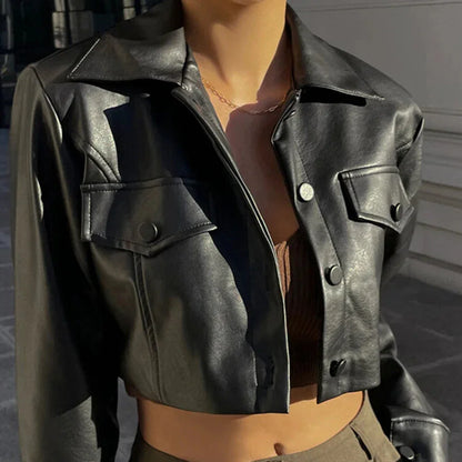 Close-up of woman wearing a cropped black leather jacket with buttoned pockets, styled with a necklace and brown top