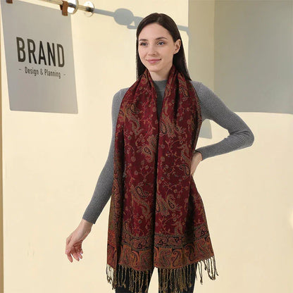 Woman modeling red paisley pashmina shawl with fringe in front of BRAN design sign