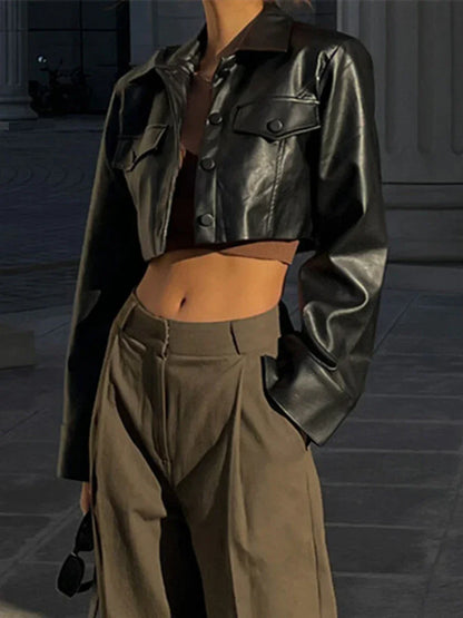 Close-up of a woman wearing a black cropped leather jacket and high-waisted brown trousers outdoors