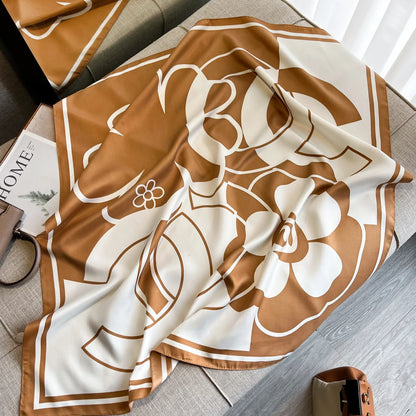 Brown and white floral silk scarf with geometric border on beige sofa