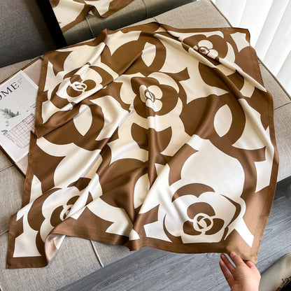 Brown and white floral silk scarf on a beige sofa with magazine nearby