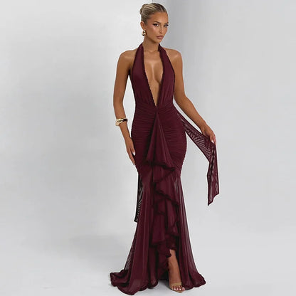 Elegant woman in a deep burgundy halter-neck evening gown with ruffle details, posing on a white backdrop
