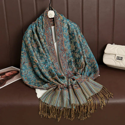Paisley patterned teal and brown silk scarf with fringe on brown sofa next to white handbag