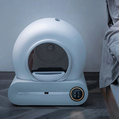 Smart self-cleaning white cat litter box with digital display placed on modern floor near bed