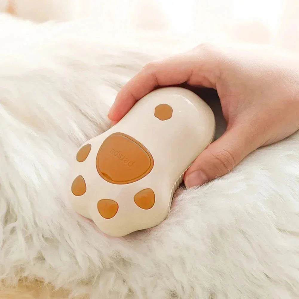 Hand holding steam grooming brush shaped like a paw on white pet fur