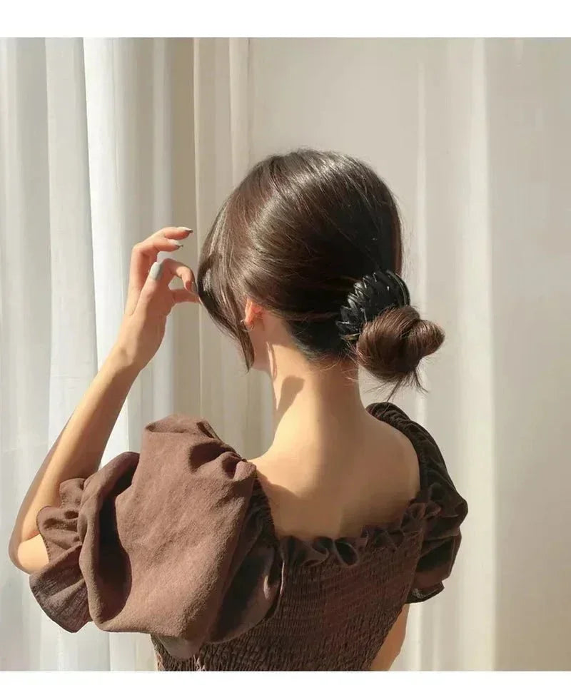 Woman wearing bird nest ponytail hair clip with low bun and brown puff sleeve dress
