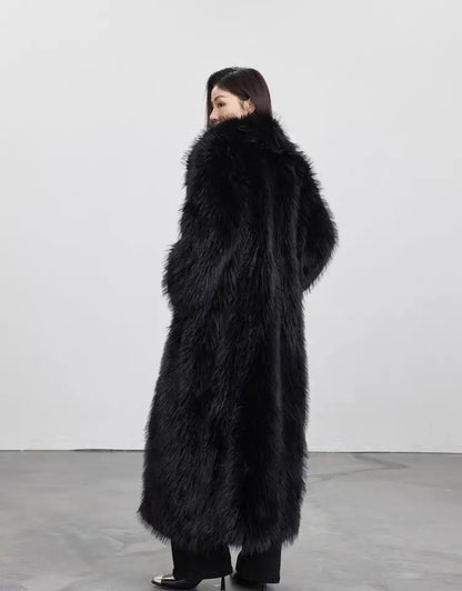 Woman wearing a long black faux fur winter coat standing in a minimalist studio