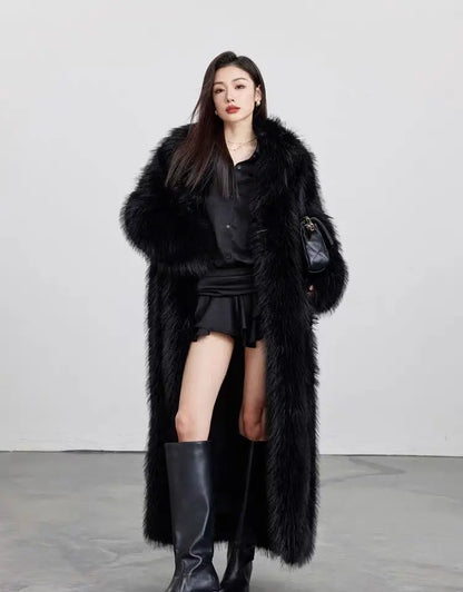 Model wearing a long black faux fur winter coat, black shirt, skirt, and knee-high black boots in studio