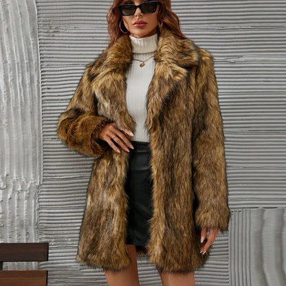 Woman wearing brown faux fur maxi coat over white turtleneck and black skirt against gray textured wall